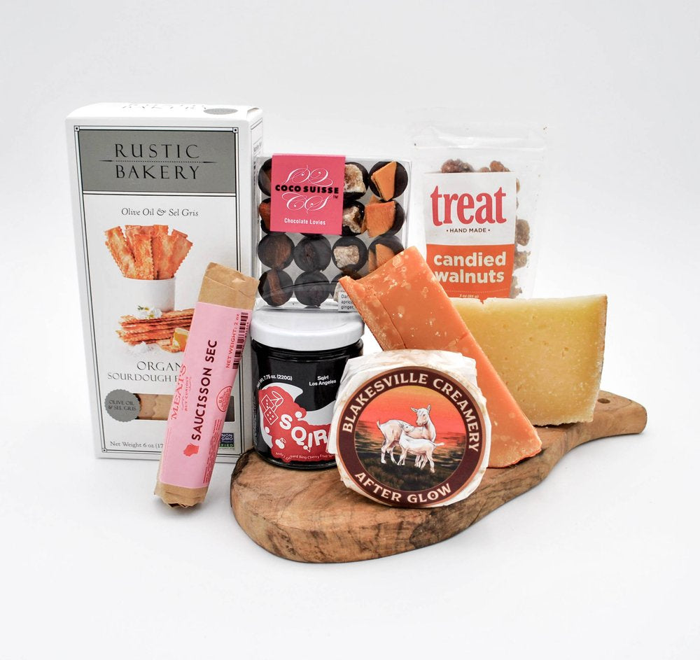 Gift basket filled with gourmet cheeses, salami, jam, chocolate, nuts, and specialty goods.