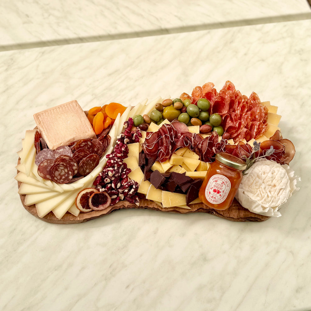 Assorted charcuterie board with meats, cheeses, and fruits on a wooden board.