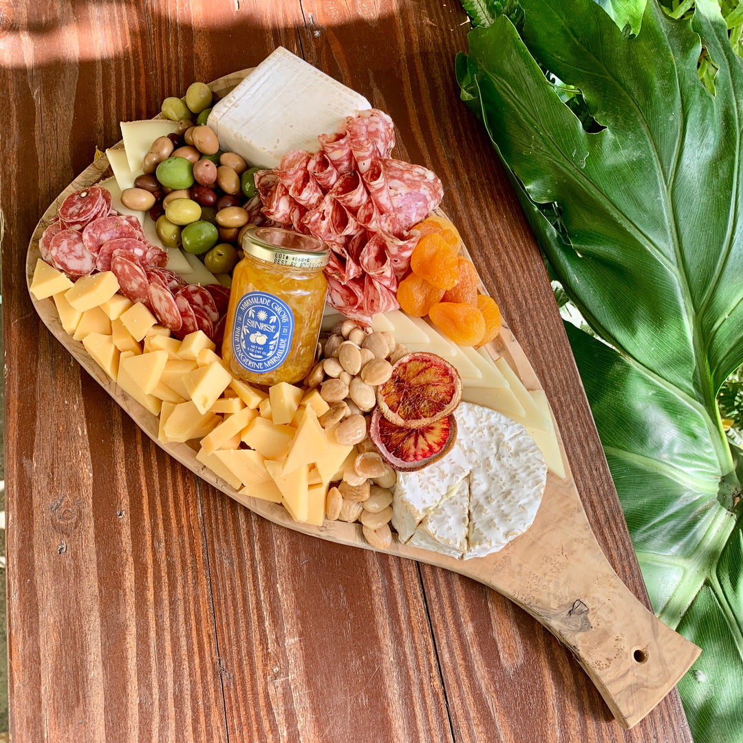 Cheese platter with various cheeses, cured meats, dried fruit, nuts and olives on an olive wood board.