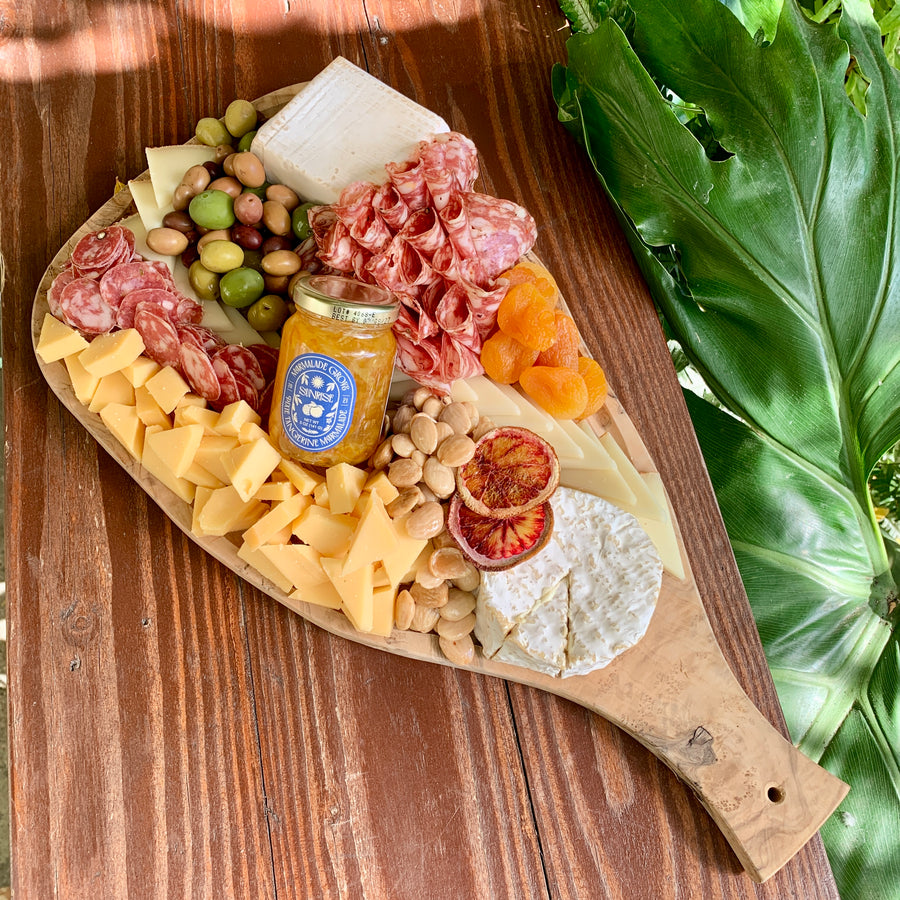 Cheese platter with various cheeses, cured meats, dried fruit, nuts and olives on an olive wood board.
